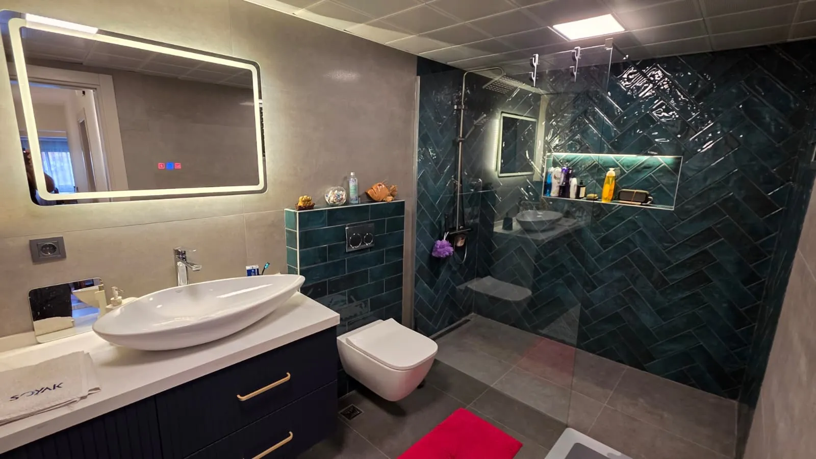 Koyu yeşil balıksırtı seramikli, lacivert dolaplı banyo