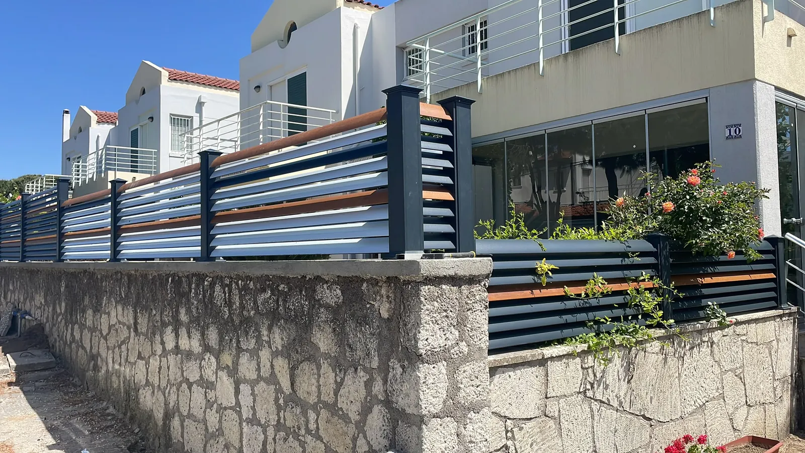 Taş bahçe duvarı üzerinde ahşap detaylı korkuluk